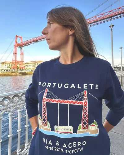 Mujer con la sudadera Portugalete · Ría & Acero delante del Puente Bizkaia, mirando al río