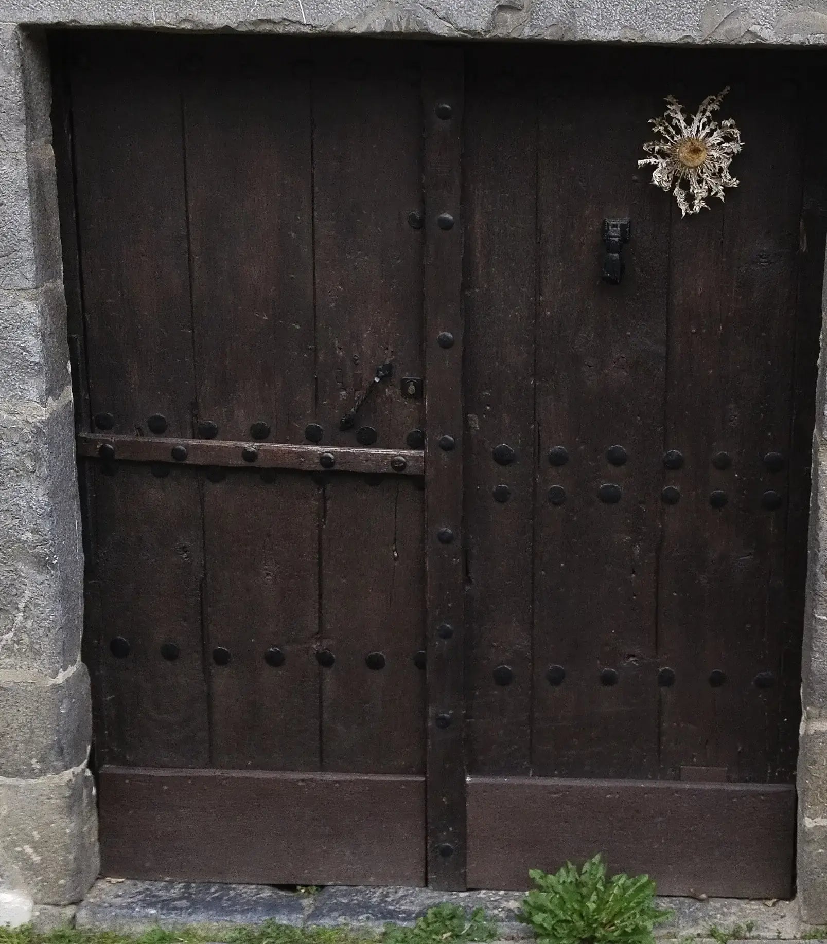 Puerta oscura de madera de un caserío guipuzcoano, con un eguzkilore clavado arriba a la derecha